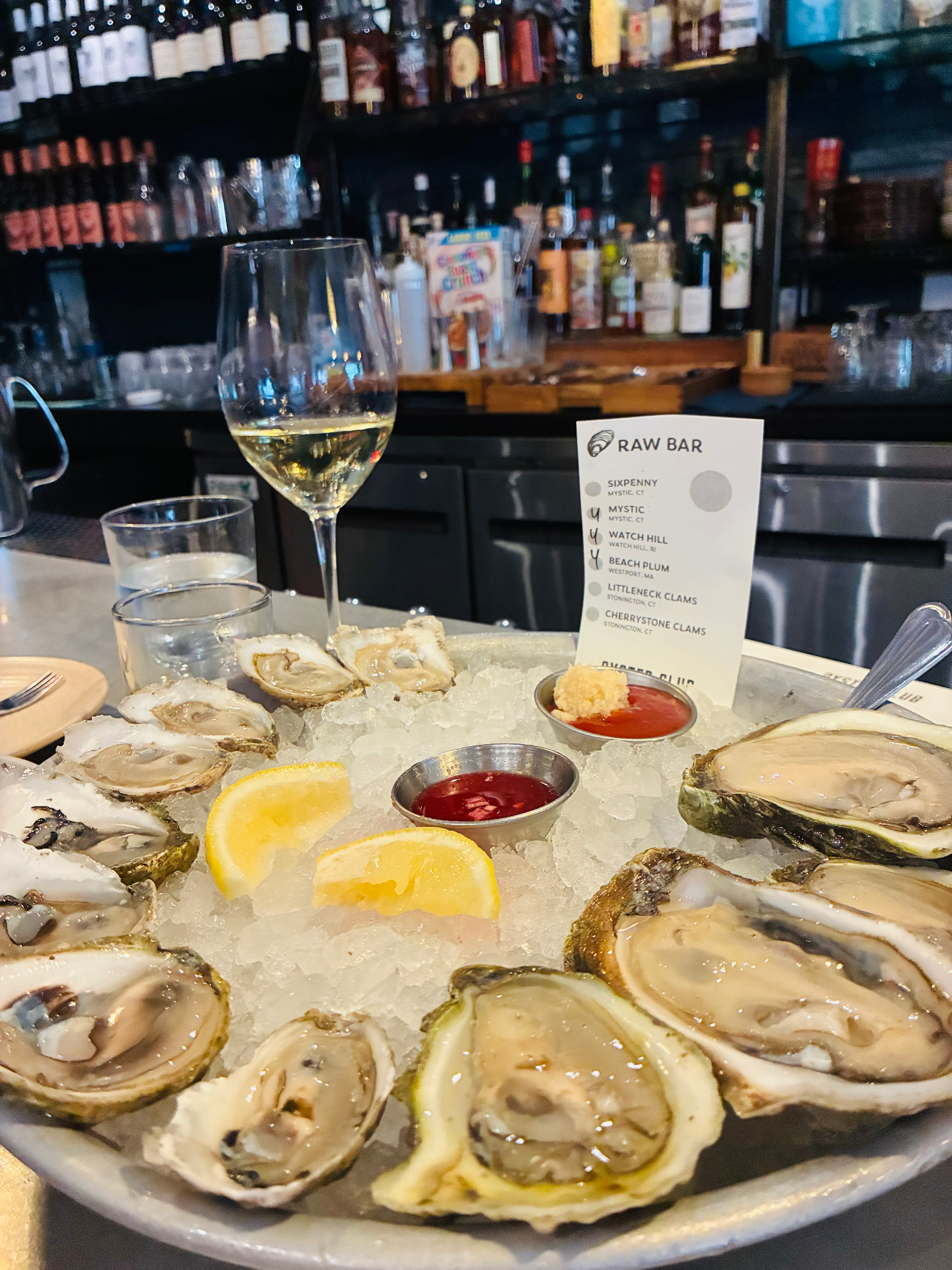 Raw bar oyster platter with a glass of white wine